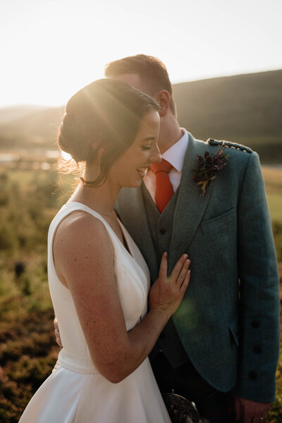 A couple embrace beneath the golden setting sun at Mar Lodge.