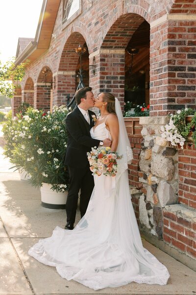 ride and groom kissing outside the century room at gbric events , a unique wedding venue in st. louis