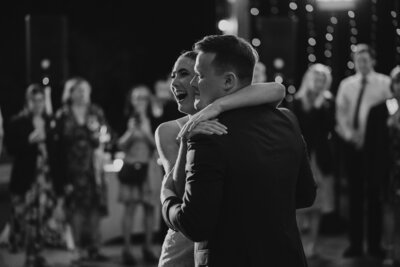 A black and white photo of a couple hugging each other on the dance floor