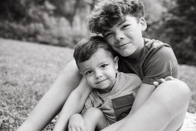 black and white portrait of brothers cuddling in the grass during a lifestyle family photography session