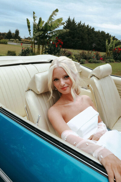 Bride sitting in a vintage blue car with sleek, simplistic hair and makeup — timeless bridal look styled by Klover Beauty for a Maryland wedding.
