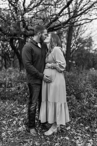 man and woman kissing holding pregnant belly