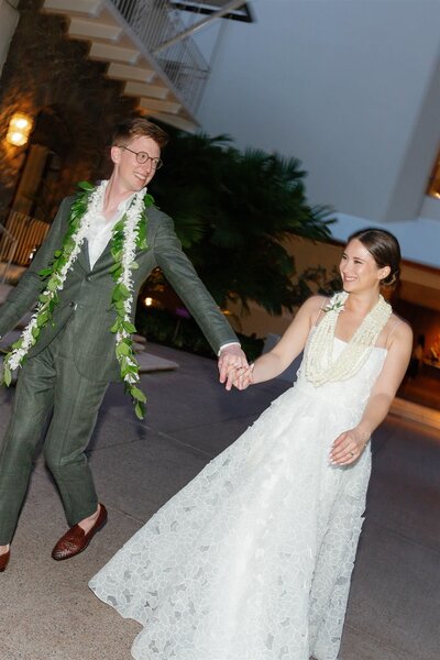 A newlywed couple laughing and holding hands and they walk together 