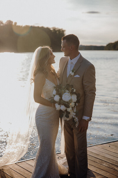 Sunset wedding at the Glastonbury boathouse. Couple in wedding attire standing on the boat dock.