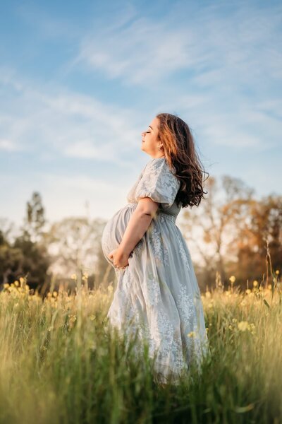 pregnant mom looking into sun with mountains in background