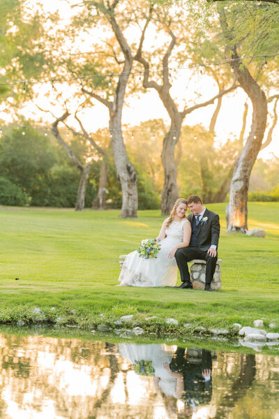 couple sitting by pond at sunset