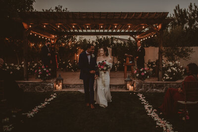 backyard wedding ceremony with interracial couple  with fairy lights and classic modern wedding dress
