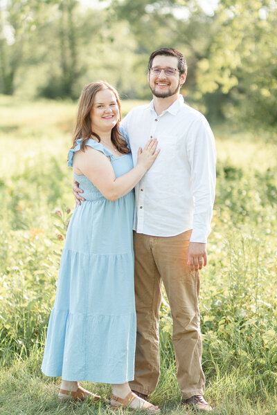 a couple posing together in a field of grass at golden hour