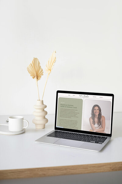A laptop on a desk with a coffee cup and a plant, representing a virtual nutritionist website workspace.