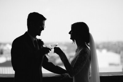 black and white photo of a bride and groom silhouette cheersing their drinks