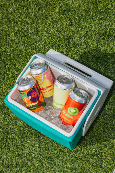 A close up image of a hand holding a seltzer can in front of a purple backdrop