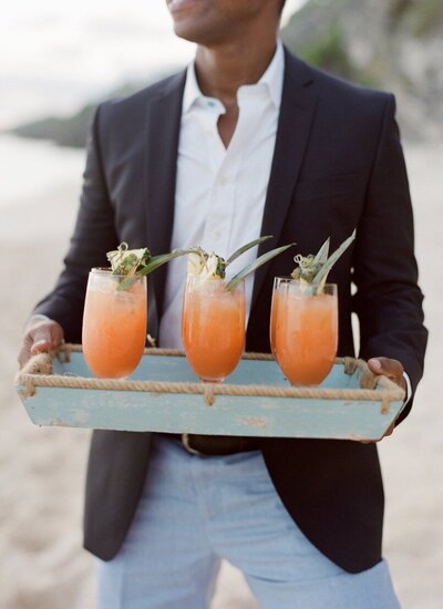 Server in suit holding a platter of cocktails