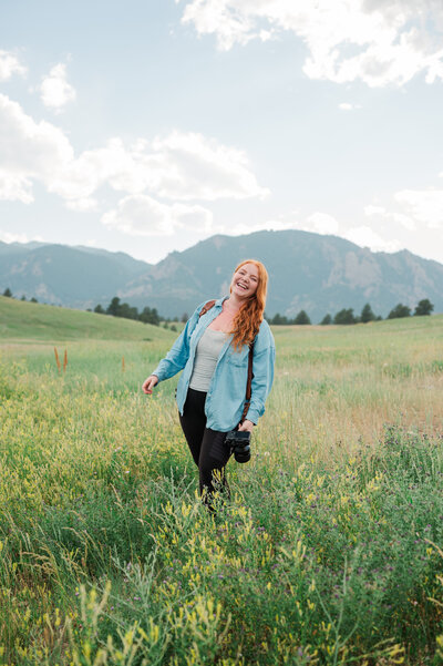 Samantha Immer walks through a field towards the mountains carrying her adventure gear in Colorado