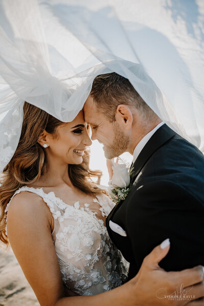 bride and groom embracing underneath bride's veil