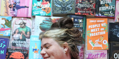 A woman's head lay on top of a pile of books.