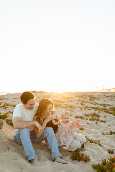 family sitting on sand together