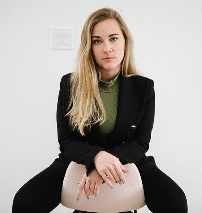 Realtor Tamara Rzan exuding confidence while comfortably seated in a chair of a pristine white home