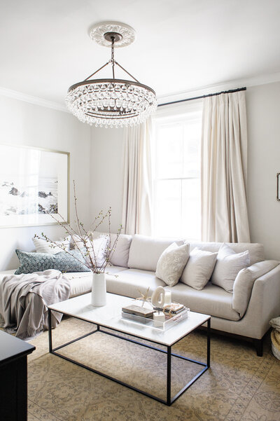 grey bedroom with recessed wall panelling and upholstered linen and wood headboard with small nightstands and gold wall sconces