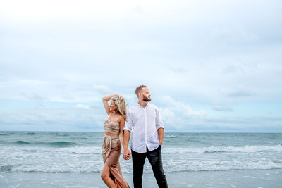 interracial couple on the beach holding hand for their engagement session