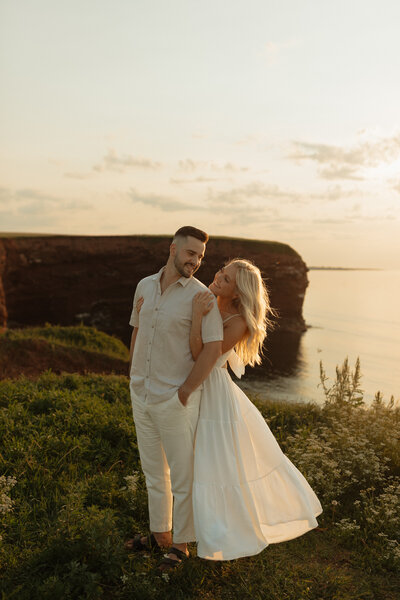couple embrace next to ocean during lifestyle photos in pei