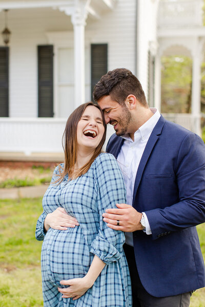 Husband and wife laughing at spring maternity session