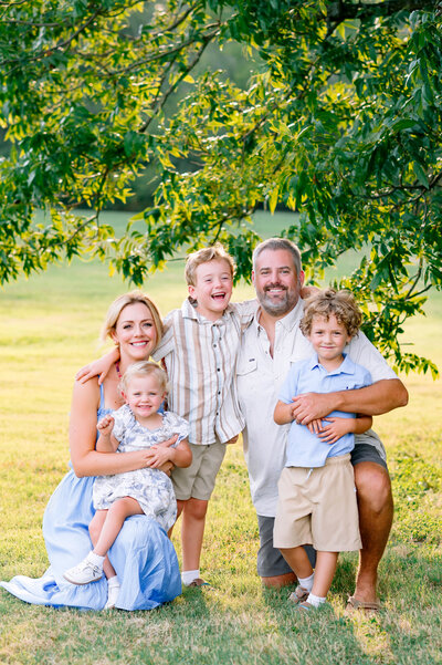 Smiling family of five posed under a large tree during a golden hour family session with Jennifer L. Kirk Photography in Allen, Texas. Specializing in joyful, timeless family photography across Allen, McKinney, and Plano.