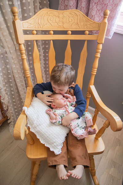 Newborn Photo of Brother kissing newborn sister on the forehead