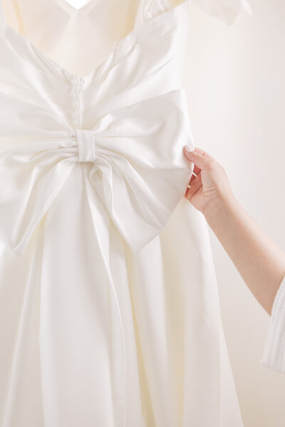 brides right hand touching the bow of her dress