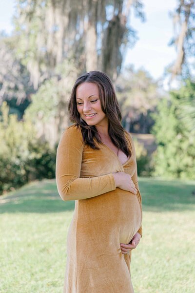 Woman holds her belly during maternity portrait session with Palmetto Bluff Photographer Lamp and Light Photography. 