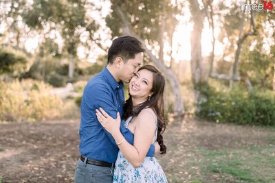 Groom to be kisses his Bride's cheek as she expresses a big smile during engagement session at the William R. Mason Regional Park in Irvine