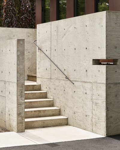 Minimalist outdoor concrete stairs and a clean steel handrail, leading you to an entrance of a home.