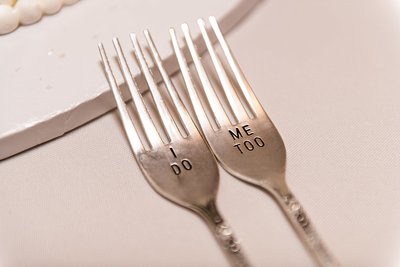 I Do, Me Too silver forks resting near a plate during a wedding reception