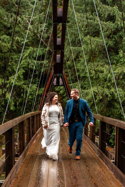 Bride and groom standing on a trail during a sunny day. Groom is wearing a backpack.