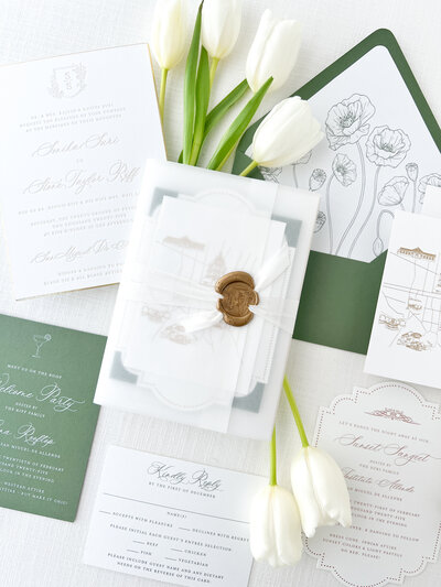 a flat lay of a white and green wedding invitation suite