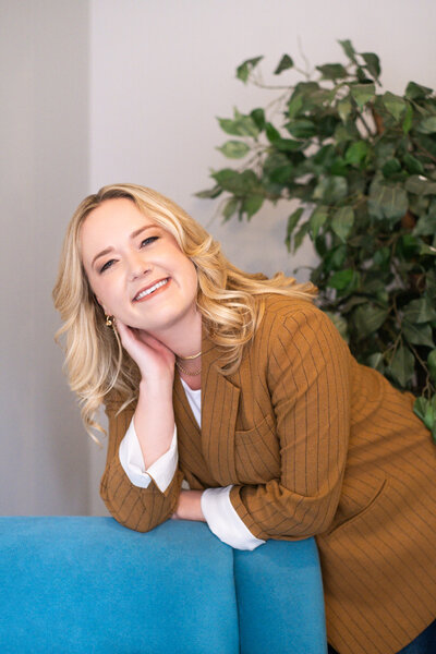 Olivia Verhulst, psychotherapist sitting on a leather couch smiling at the camera.