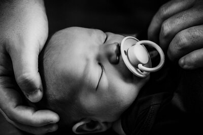 A black and white photo of a baby with a pacifier, captured during a Fresh 48 session at Winnie Palmer Hospital, Orlando.