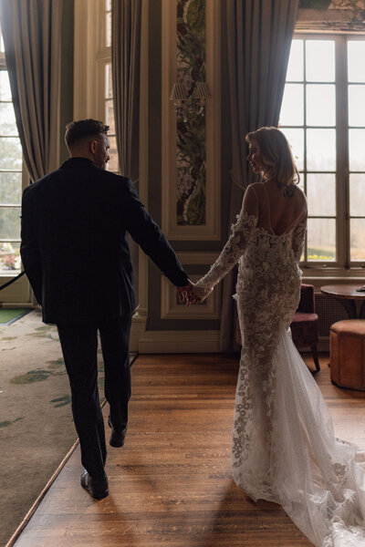 Wedding photographer captures couple taking a stroll hand in hand at their french chateau wedding.
