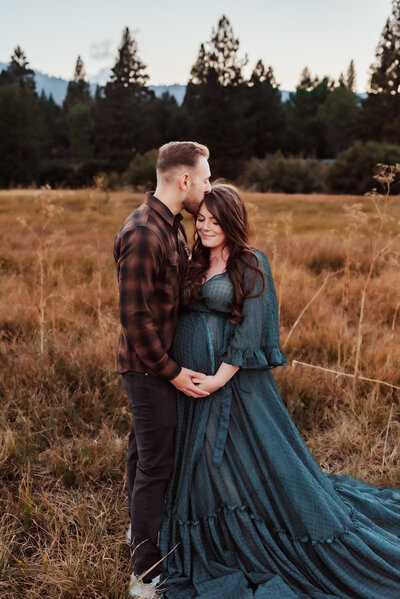Expecting couple embracing in a Reno, NV field.