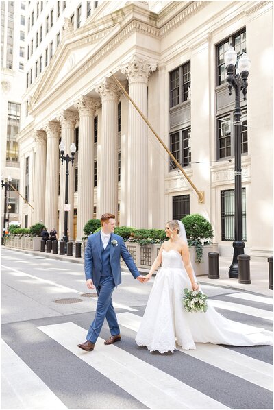 Bride and groom walking across a crosswalk for their wedding photos in downtown Chicago