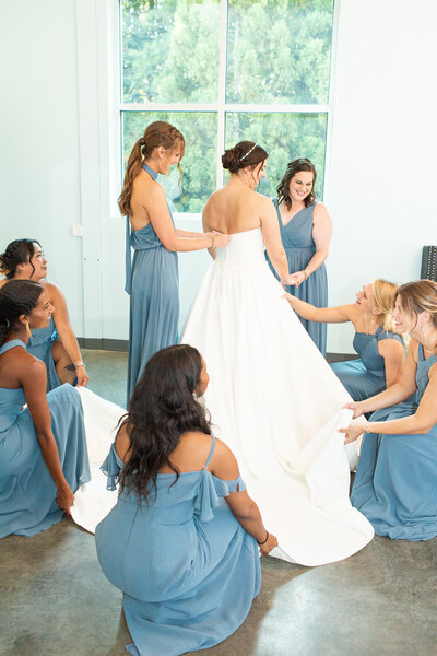 bridesmaids helping bride zip up wedding dress