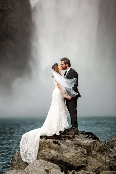 couple kissing on the rocks at the bottom of Snoqualmie Falls