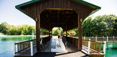 Bride and groom kiss under the covered bridge at Majestic Woods