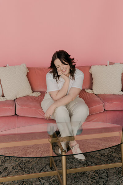 Smiling woman sitting on a pink velvet couch