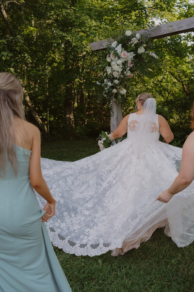 The train of a bride with the bridesmaids holding bride's dress train at Hidden Meadows in Northeast, TN