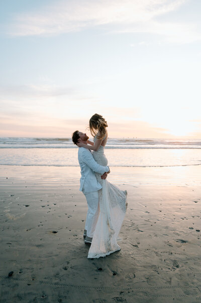 Southern California wedding photographer captures bride and groom embracing at sunset on the beach.