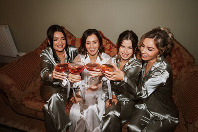 Bride and bridesmaids laughing under confetti at aswanley wedding venue