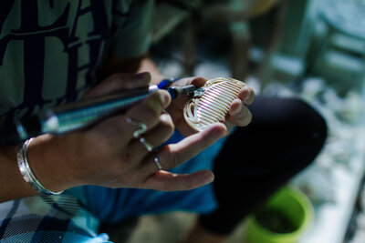 Hands of a shell jewelry artist polishing a shell comb.