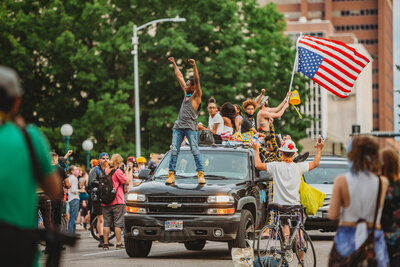 Man standing on the hood of a truck during a Black Lives Matter protest in Denver, Colorado, capturing a powerful moment of activism and solidarity.