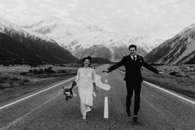 Mt Cook wedding New Zealand - couple running along the road with snow top mountains in the back ground. By Elk and Fir