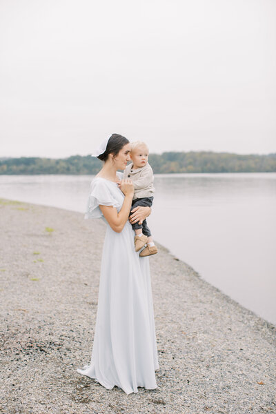 Mother standing with a toddler in her arms next to a lake